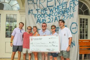 Fraternity members hold giant check for $1,634 at Phriday Phrenzy event