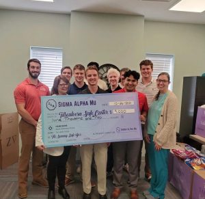 Pedro, Cole and other fraternity members present large check for $9,000 to Tuscaloosa SAFE Center employees