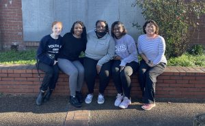 Students who served in the Beyond Bama Memphis trip sit on a brick bench for a picture