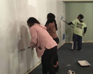 students paint the interior of a building