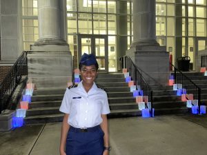 Jahnaya poses in front of red, white, and blue luminaries set up in front of the UA Student Center
