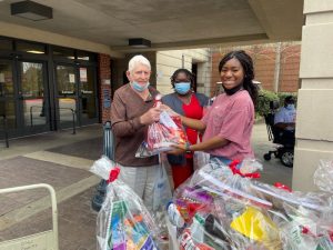 UA student Jahnaya hands a care basket to a veteran at the Tuscaloosa VA Medical Center